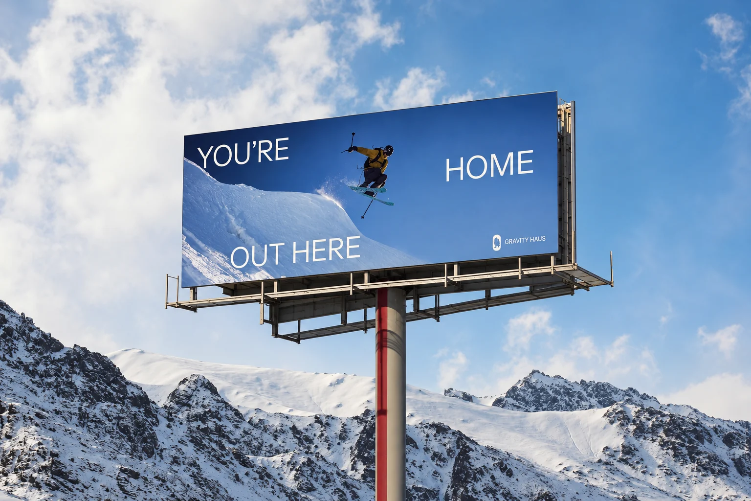 Gravity Haus You’re Home Out Here billboard featuring a skier above snow-covered mountains