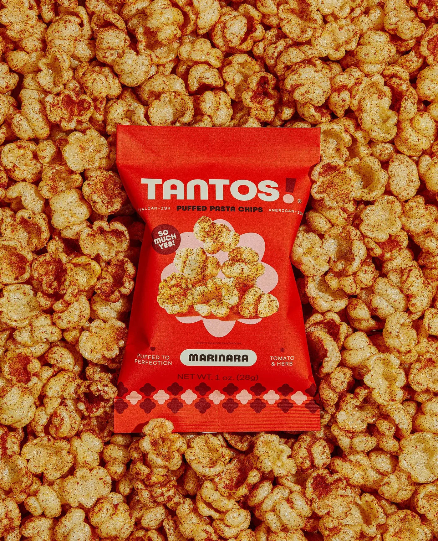 Red Tantos Marinara puffed pasta chips bag surrounded by seasoned pasta chips