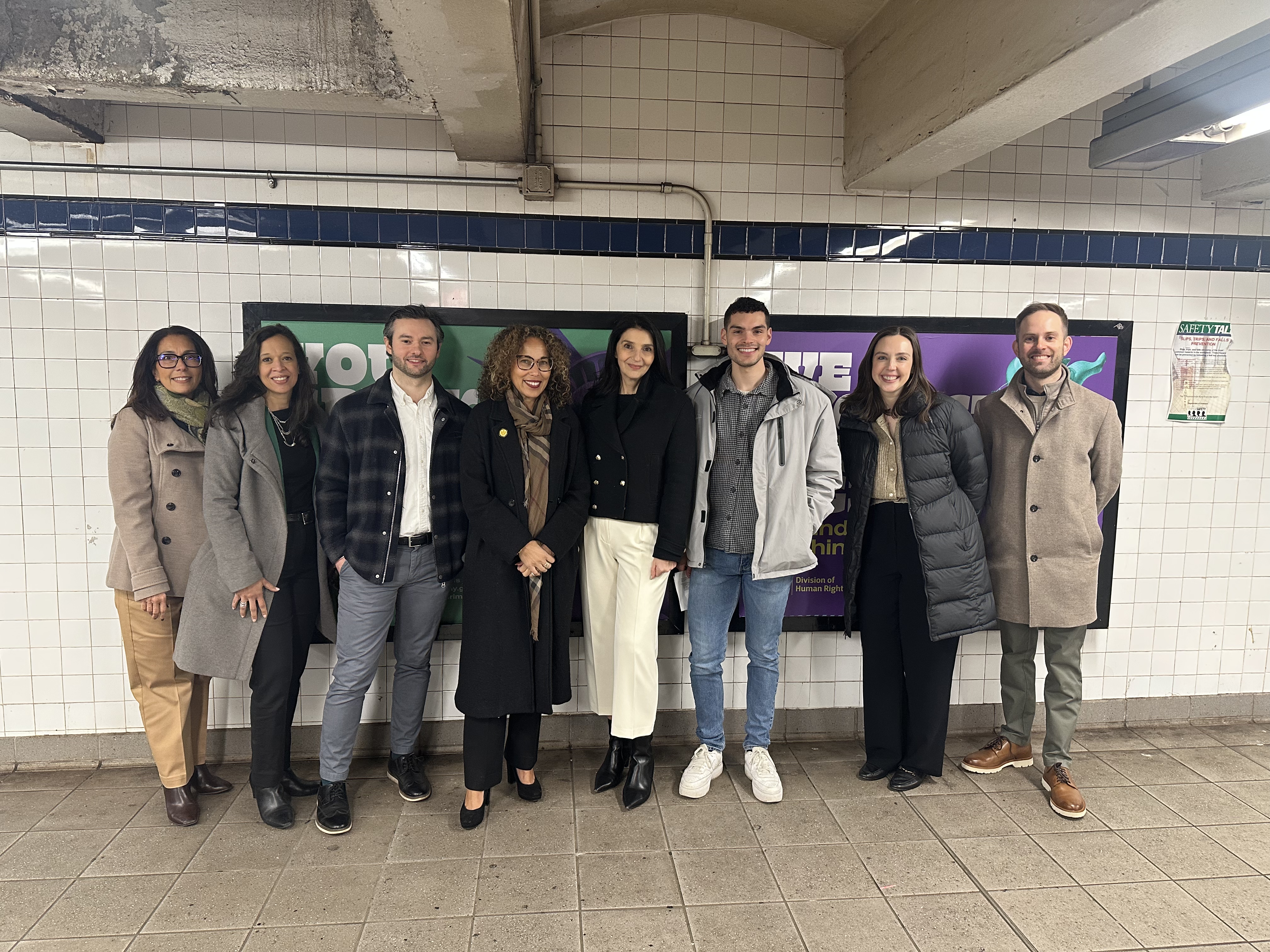 OpAD Media employees standing with New York State Division of Human Rights client team together in a New York City subway station in front of media placements